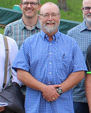 Man in a group photo outside wearing a plaid shirt.