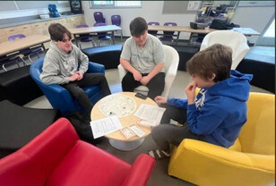 Three teens sit in a circle playing a game.
