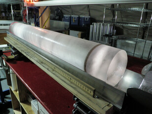 Ice core in a lab setting looks like a long semi-transparent cylinder of ice with a prominent black ring near one end.