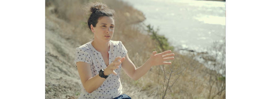 Woman being interviewed by herself with a river in the background on a sunny day.