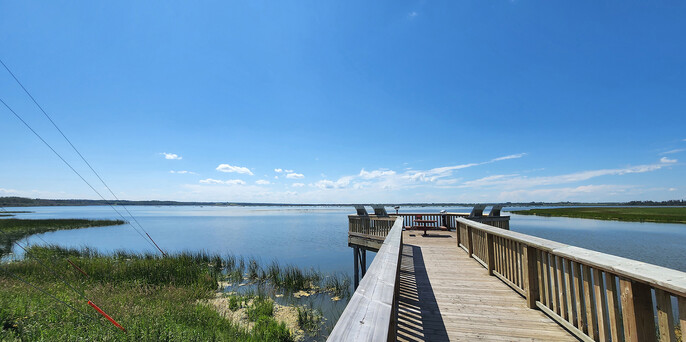 A wooden dock with a grassy shoreline at Big Lake on a sunny day.