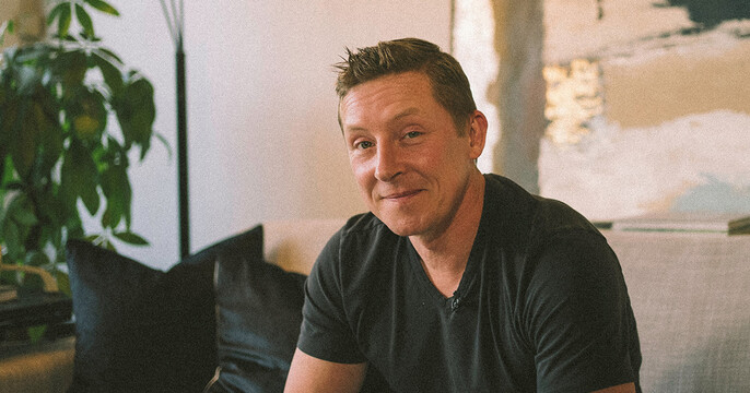 Josh Classen poses for a casual photo on a couch.